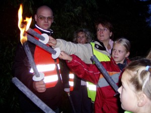 Andre Becker (l) beherrscht das Spiel mit dem Feuer und lässt hier die Funken an Alexandra Kringe (halbrechts) und Giulia Stockhammer (rechts) überspringen. Aus dem Hintergrund verfolgt Carmen Emmerich das Geschehen. Vorne rechts am Bildrand wartet Daniela Hagedorn auf einen freien Platz an der Feuerstelle. 